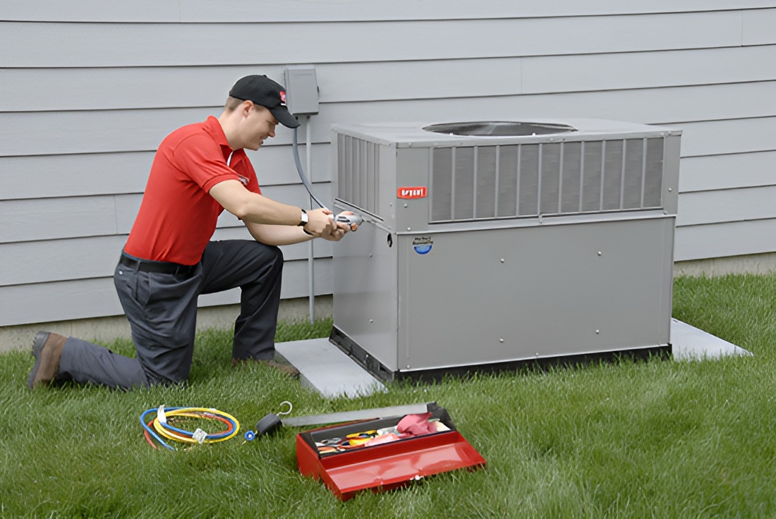 Person kneeling with service gauges beside an outdoor air conditioning condenser