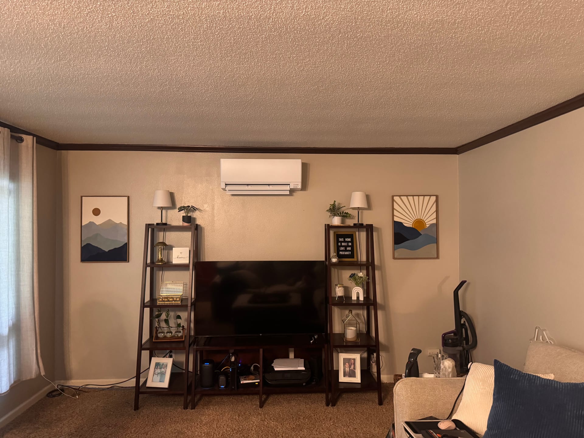 A wall-mounted ductless indoor unit above a living room entertainment center